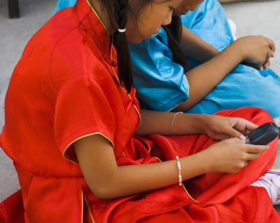 Thai girls using mobile telephone in costume of dance troupe.