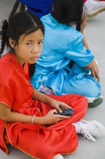 Thai girls using mobile telephone in costume of dance troupe.