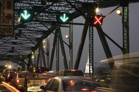 Traffic flow control in evening rush hour on Saphan Phut Memorial Bridge illuminated temple stupa in the background.