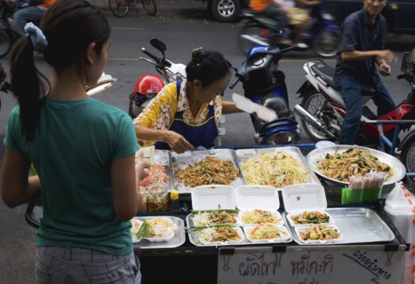 Street vendor and daughter sell take away Pad-thai the national fried noodle classic dish.