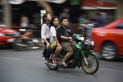 Young Thai women on motorcycle without helmets helmet in shopping basket blurred motion.