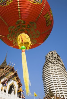 Wat Yannawa temple roof and unfinished apartment block from 1990s Asian financial crash with red lanterns at Chinese New Year.
