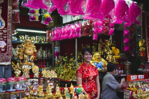 Young woman in Cheong sam chinese dress at shop selling decorations for Chinese New Year.