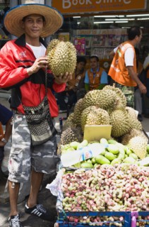Thai man selling Durian fruit from cart.