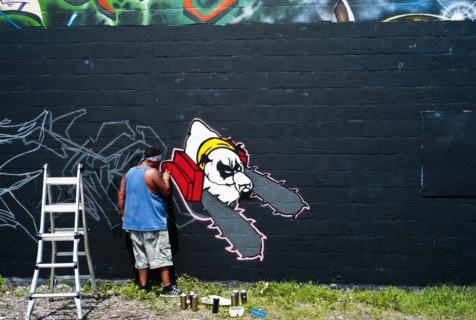 Graffiti artist painting wall.