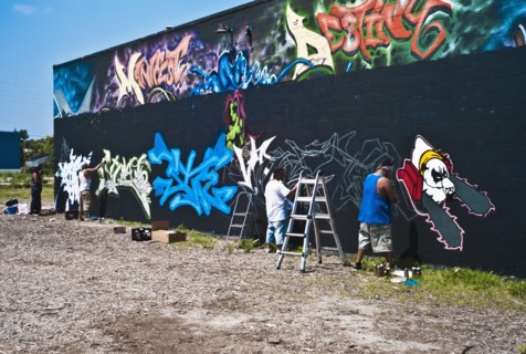 Graffiti artists painting wall.