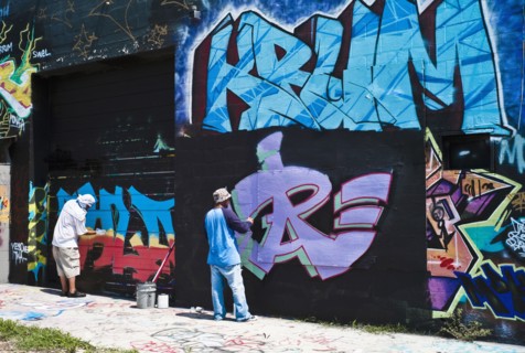 Graffiti artists painting wall.