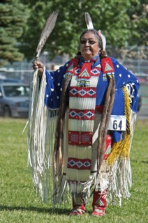 Blackfoot dancer in blue cape trimmed withotter fur and porcupine quill apron holding a feather fan in the Women's Traditional Dance at the Blackfoot Arts & Heritage Festival Pow Wow organized by Park...