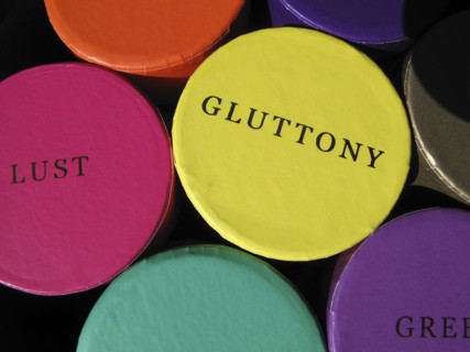 Colourful trinket boxes on a market displaying the words of the Seven Deadly Sins.