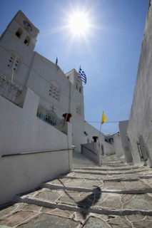 Portrait format low angle photograph of a typical alley found only at Cyclades island complex with the church of Agios Spyridonas on the left hand side.