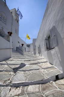 Portrait format low angle photograph of a typical alley found only at Cyclades island complex with the church of Agios Spyridonas on the left hand side.