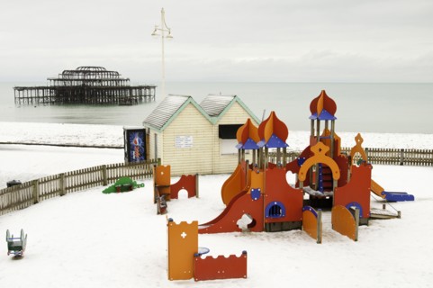 West Pier during winter with snow on the beach and childrens play area in the foreground.