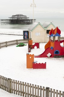 West Pier during winter with snow on the beach and childrens play area in the foreground.