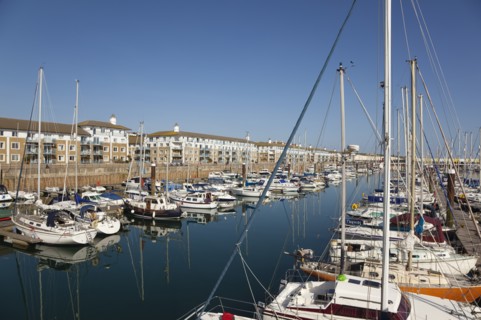 View over boats moored in the Marina with apartment buildings behind.