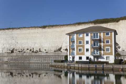 Apartment building in empty marina with chalk cliffs behind.