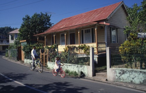 West Indies, Jamaica , Port Antonio, Roadside housing with veranda and walled garden. Boy and young