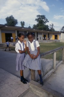 West Indies, Jamaica, Education, Two schoolgirls in checked dresses in playground in front of