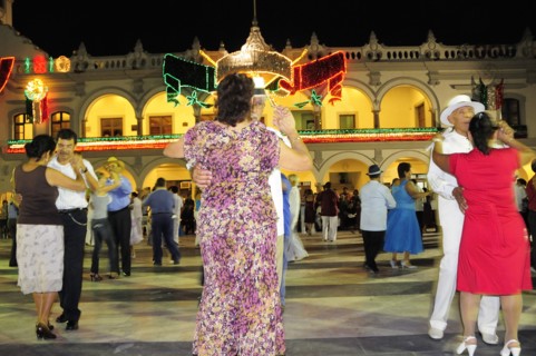 Mexico, Veracruz, Couples dancing in the Zocalo at night illuminated decorations in the national