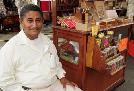 Mexico, Veracruz, Cigar seller in the Zocalo seated beside mobile stand with display of different
