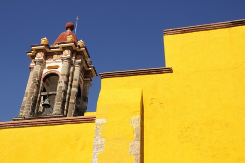 Mexico, Bajio, San Miguel de Allende, Part view of bright yellow exterior wall and church bell