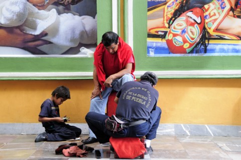 Mexico, Puebla, Shoeshine stand in front of posters. Photo : Nick Bonetti