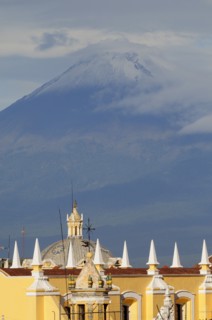 Mexico, Puebla, View of volcanic peak of Popocatepetl wreathed in cloud with Puebla rooftops in