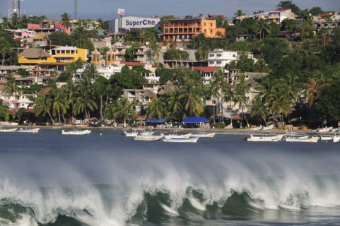 Mexico, Oaxaca, Puerto Escondido, Playa Principal Breaking waves and boats overlooked by buildings