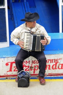 Mexico, Michoacan, Patzcuaro, Lago Patzcuaro Musician playing the accordion sitting on painted boat