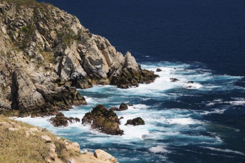Mexico, Oaxaca, Huatulco, Waves breaking against rocky coastline.. Photo : Nick Bonetti