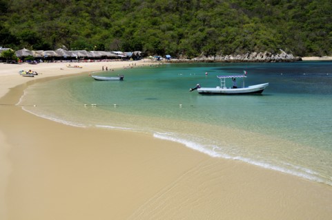 Mexico, Oaxaca, Huatulco, Playa La Entrega Stretch of sandy beach lined with thatched open fronted