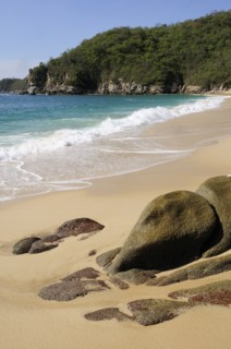 Mexico, Oaxaca, Huatulco, Bahia Chahue Rocks and deserted sandy beach with surf breaking on shore