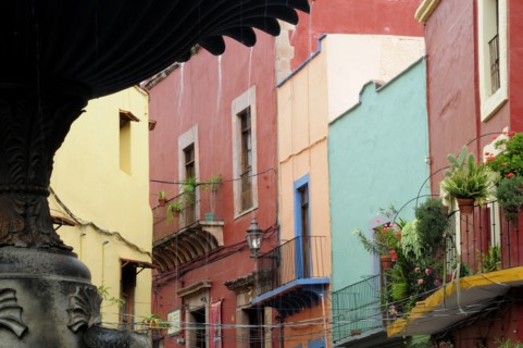 Mexico, Bajio, Guanajuato, Fountain detail in foreground of colourful buildings on Plaza del
