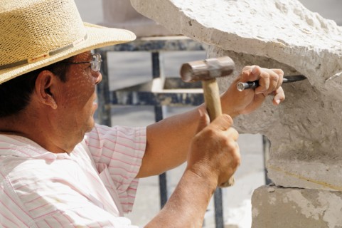 Mexico, Jalisco, Guadalajara, Plaza de la Liberacion Sculptor working stone with hammer and chisel.