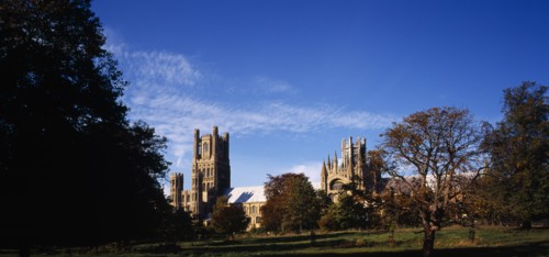 England, Cambridgeshire, Ely, View across meadow with trees in Autumn colours towards exterior of