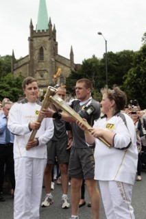 England, Kent, Tunbridge Wells, Olympic Torch relay runners handing over torch by exchanging the