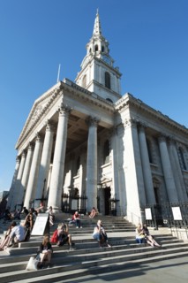 England, London, Trafalgar Square tourists sat on the steps of St Martin in the Fields Church.