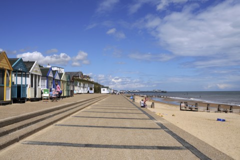 England, Suffolk, Southwold, Beach Huts near the pier with Sea Defences and Holidaymakers. Photo :