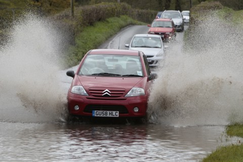 England, Kent, Flooding, Flooded country road with cars driving slowly through waters. Photo : Sean