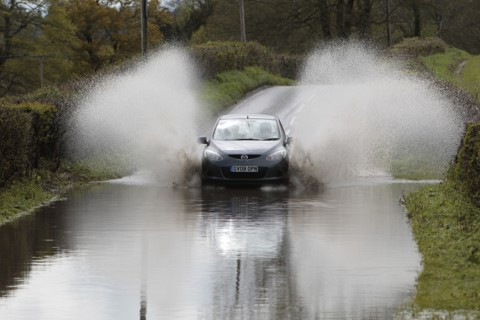 England, Kent, Flooding, Flooded country road with cars driving slowly through waters. Photo : Sean