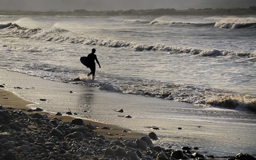 Ireland, County Sligo, Strandhill, Silhouette of surfer with surfboard heading into the sea. Photo