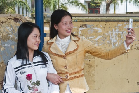 Vietnam, People, Two Young Ladies taking a picture of them selves with a camera phone. 
Photo