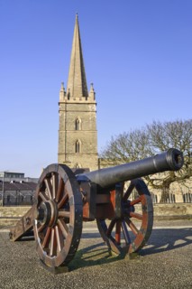 Ireland, North, Derry, St Columb's Cathedral with cannon on city walls in the foreground. 
Photo