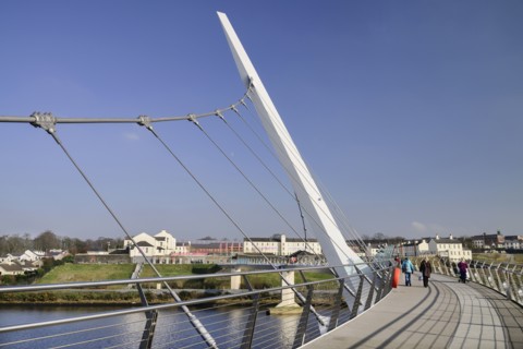 Ireland, North, Derry, The Peace Bridge over the River Foyle opened in 2011 with the former Ebrington Barracks in the background.