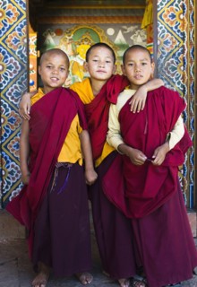 Bhutan, Punakha, Three young novice monks standing in doorway of Chimi Lakhang temple in the old