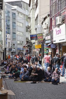 Turkey, Istanbul, Fatih, Sultanahmet, Men sat in street in readiness for midday prayers. 
Photo