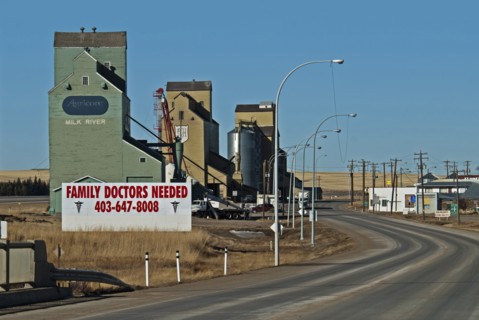 Canada, Alberta, Milk River, Old wooden grain silos or elevators still in use  Large sign announcing Family Doctors Needed for this small town near the USA border.