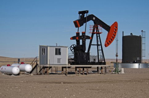 Canada, Alberta, Milk River Ridge, Oil pump jack or nodding donkey and storage tank on the edge of