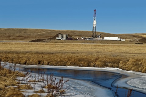 Canada, Alberta, Del Bonita, Fracking near a water source for tight shale oil and gas on the edge of the Bakken play. Ensign Energy of Calgary drilling rig  water storage tanks and road tanker. The wa...