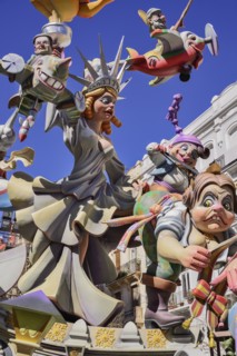Spain, Valencia Province, Valencia, Papier Mache figure of a woman resembling the Statue of Liberty with various other figures flying around her during Las Fallas festival.