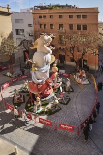 Spain, Valencia Province, Valencia, Papier Mache falla scene with onlookers viewing a giant figure of a lady in the street at Torres de Quart during Las Fallas festival.